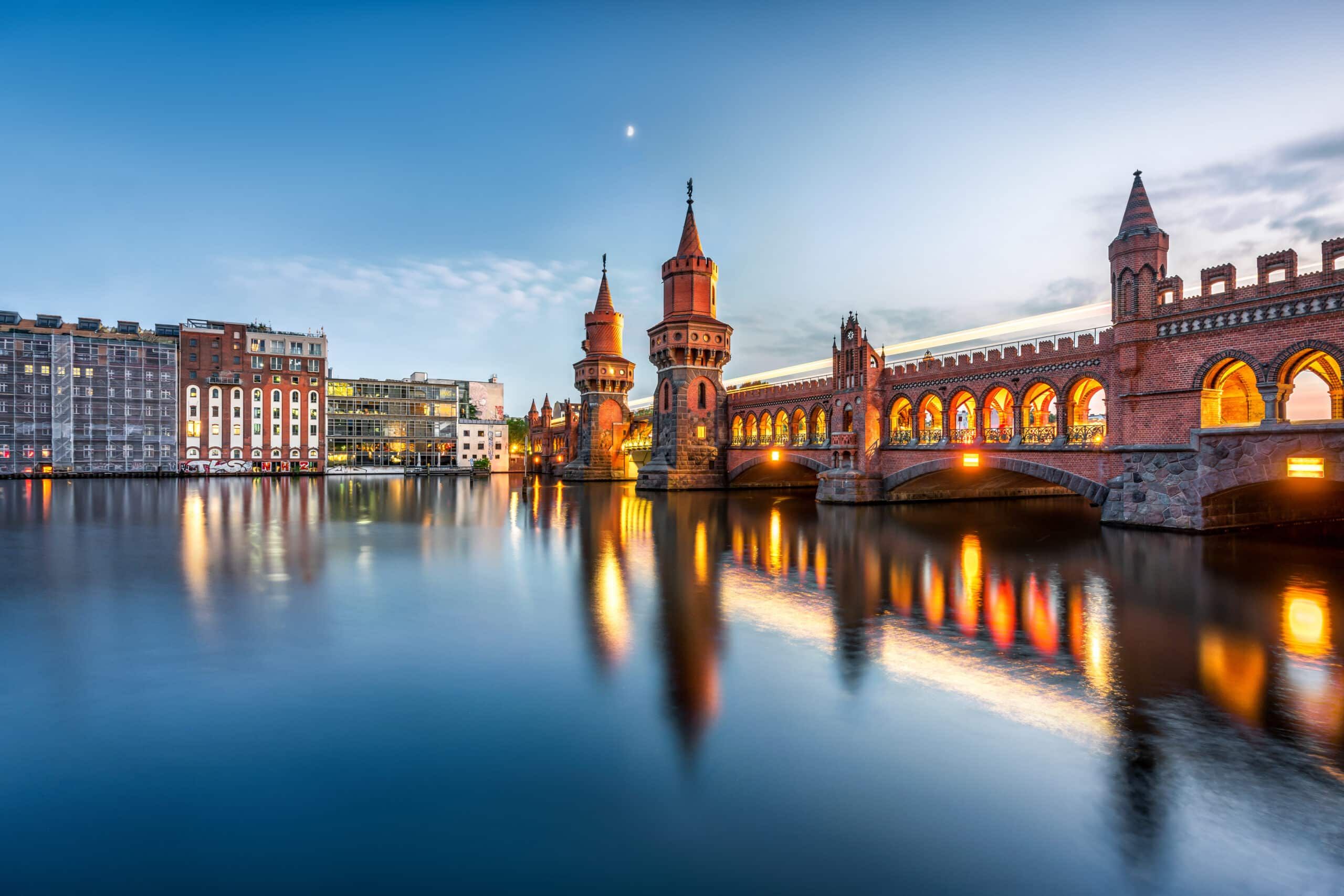 Panoramablick auf die historische Oberbaumbrücke in Berlin bei Dämmerung mit Klinkerbögen und Spiegelung in der Spree