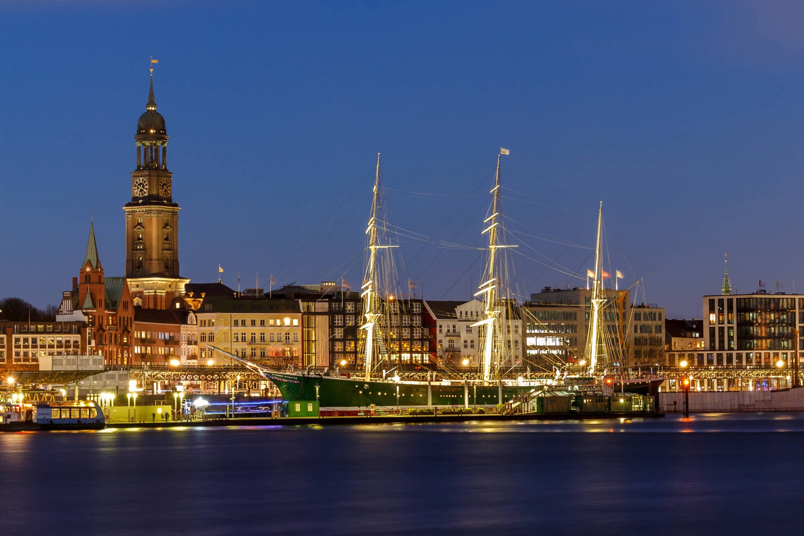 Mehrfamilienhäuser an Uferpromenade frontal bei Dämmerung mit Klinkerfassade und Schiffsanleger