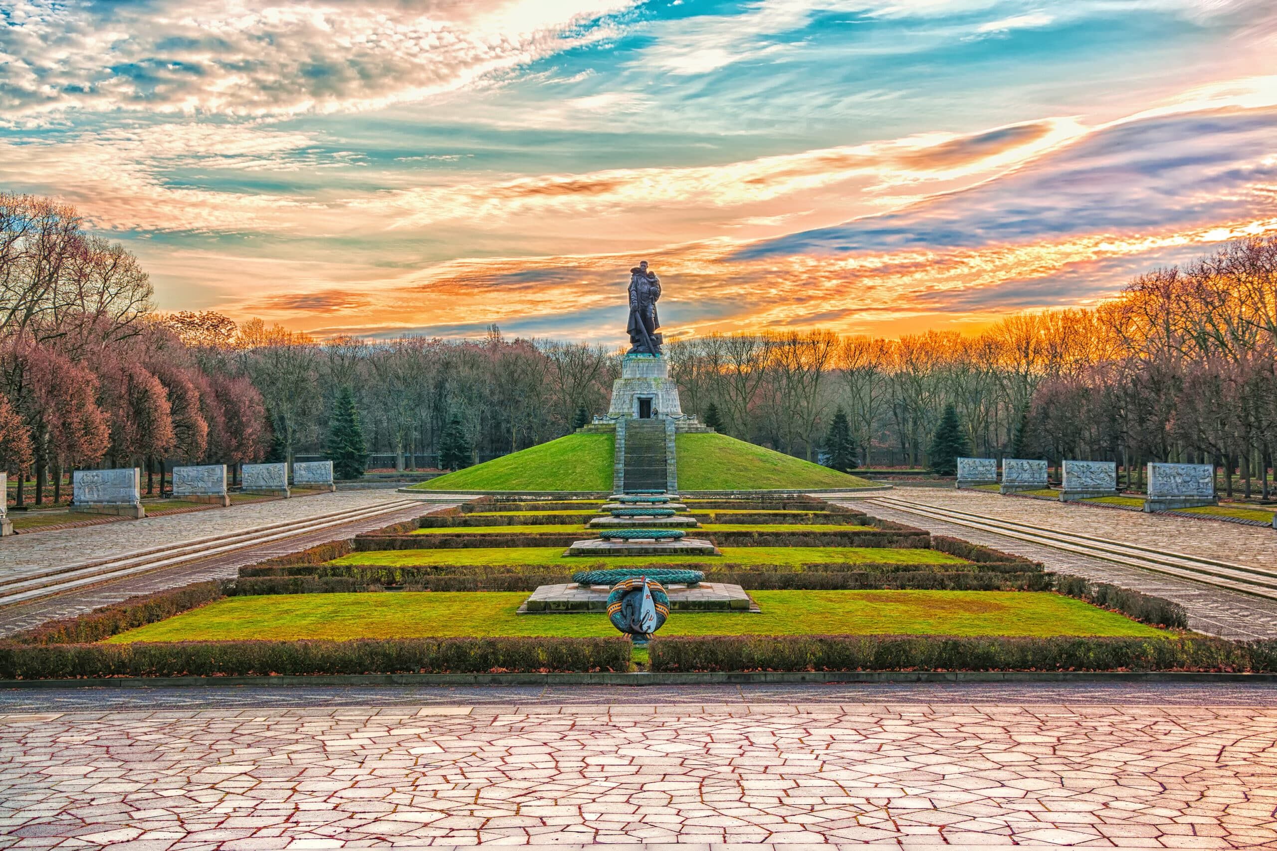 Parkansicht im Treptower Park Berlin mit sowjetischem Soldatendenkmal auf grünem Hügel und steinernen Flachreliefs