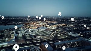 Vogelperspektive auf beleuchtete Stadtaussicht bei Dämmerung mit digitalen Standortmarkern