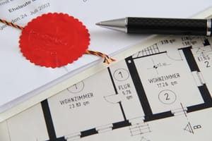 Nahe Ansicht eines roten Notarsiegels und Kugelschreibers auf einem Grundrissplan eines Wohnzimmers